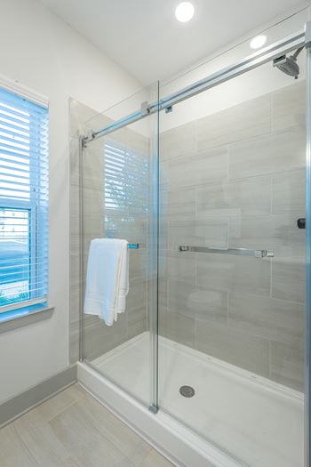 Anthem Apartments a shower with a glass door and tile floors and walls